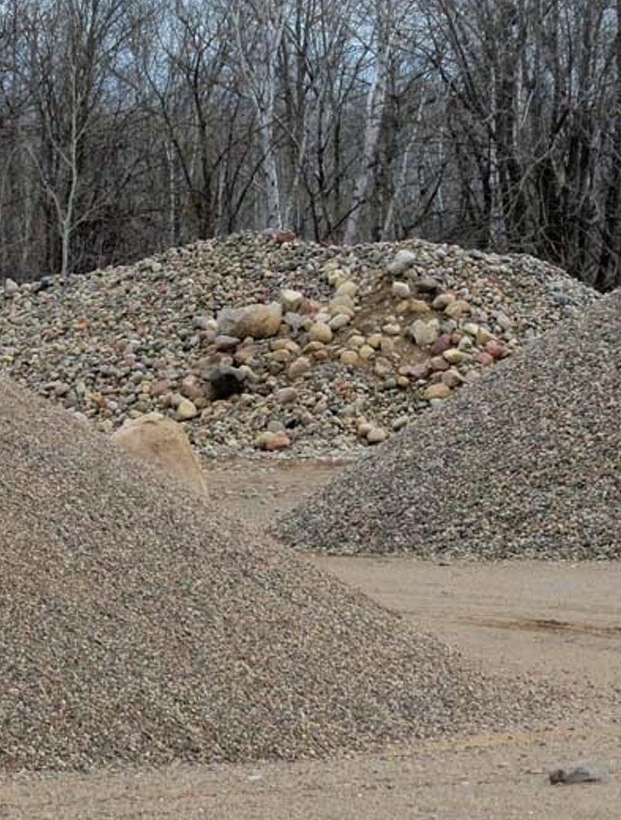 A dump truck dumping gravel on excavation site.   Vertical.